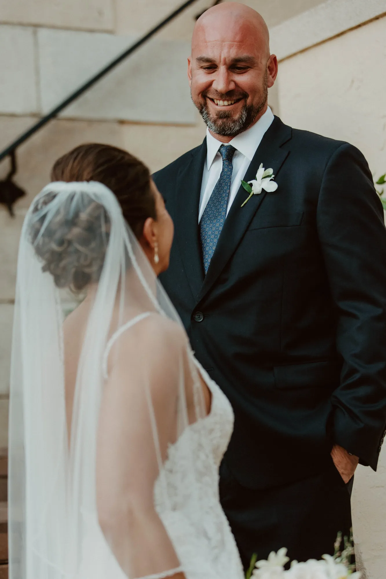 Groom smiling down at his bride, seen over her veiled shoulder