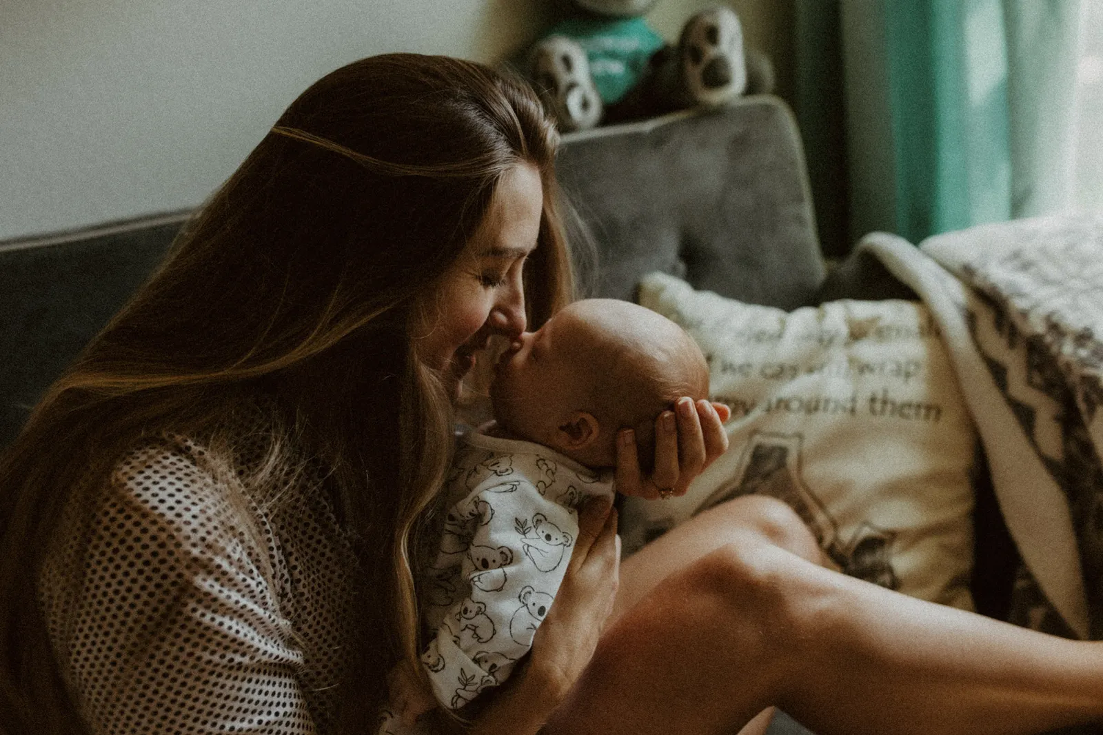 Mother nuzzling noses with her newborn on the nursery couch