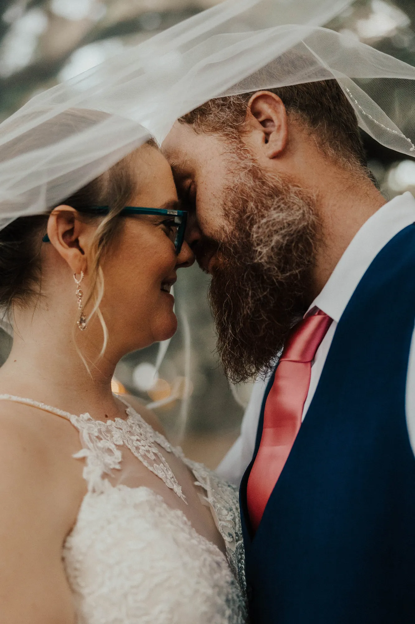 Bride and groom touching foreheads beneath her veil at Wandering Oaks