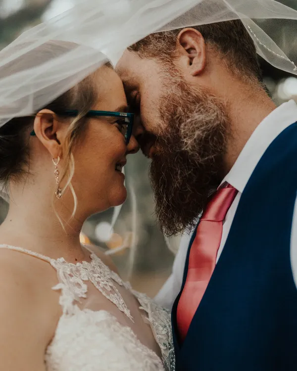 Bride and groom touching foreheads beneath her veil at Wandering Oaks