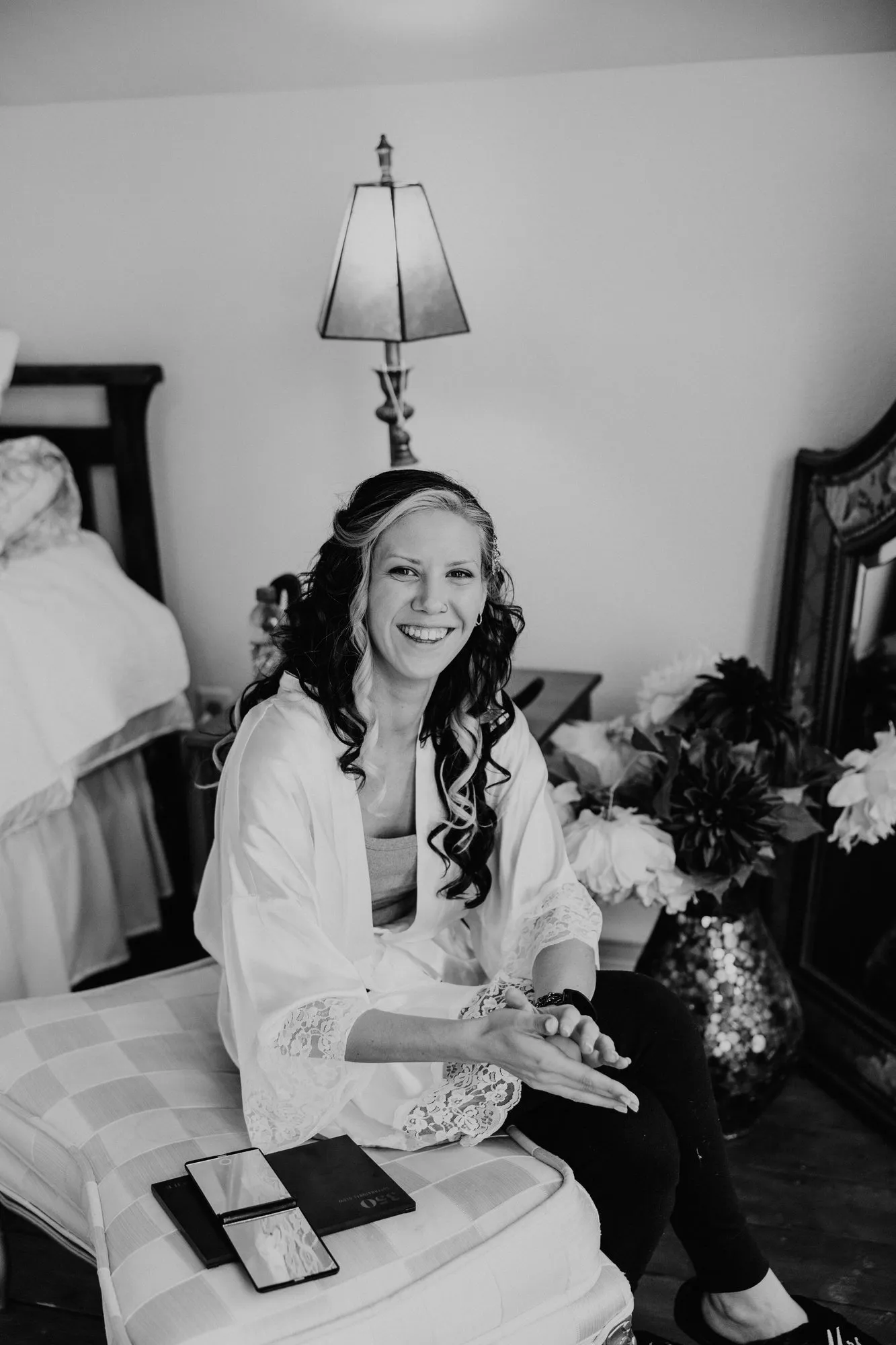 Bride in a robe laughing while she gets ready, in black and white