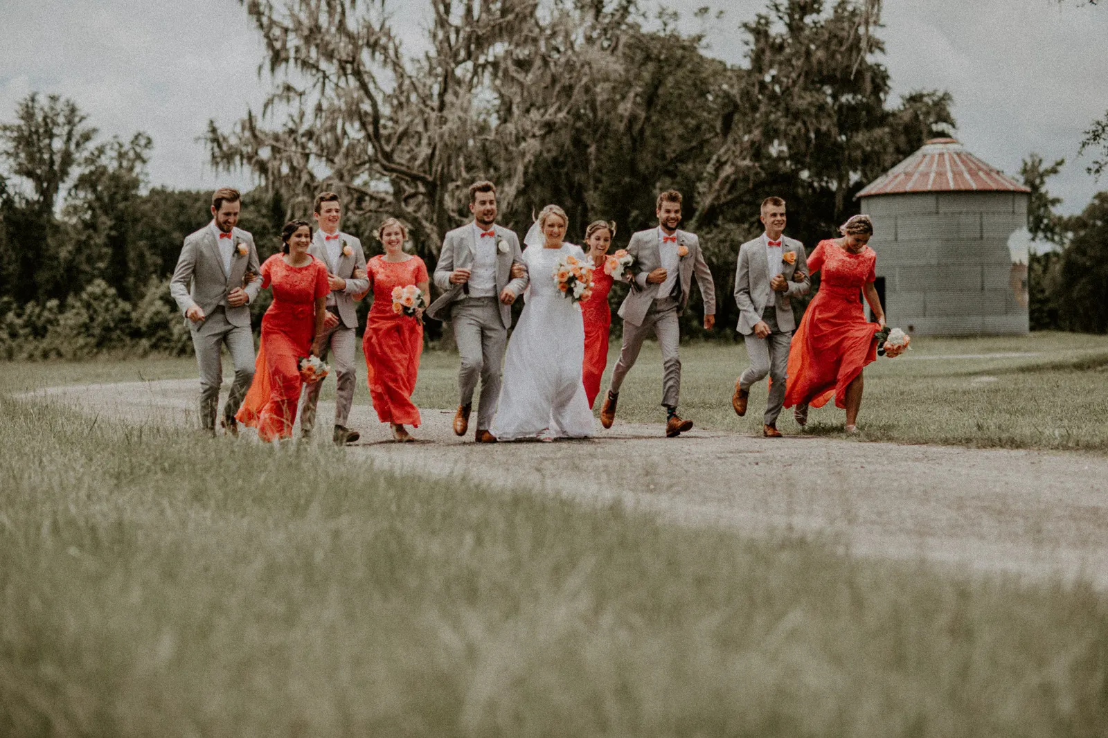 Wedding party walking down a country lane past a grain silo