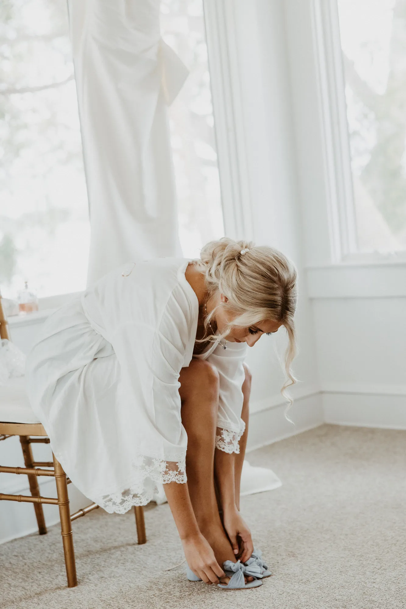 Bride in a robe fastening her blue bow shoes