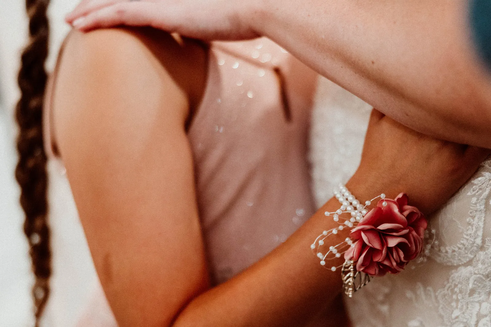Wrist corsage of pink ribbon flowers on an arm around a girl's shoulders