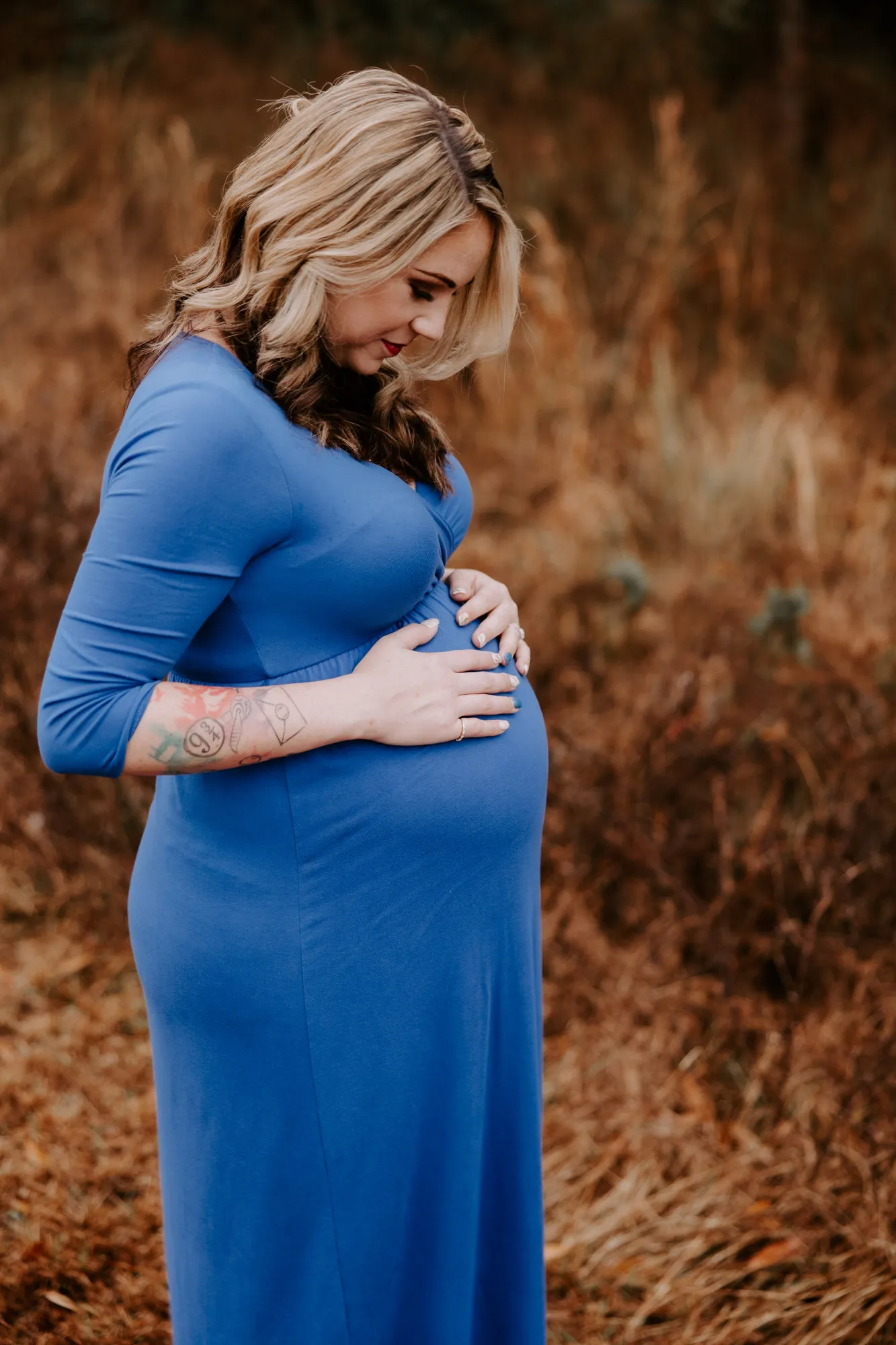 Expectant mother in a long blue dress in an autumn field