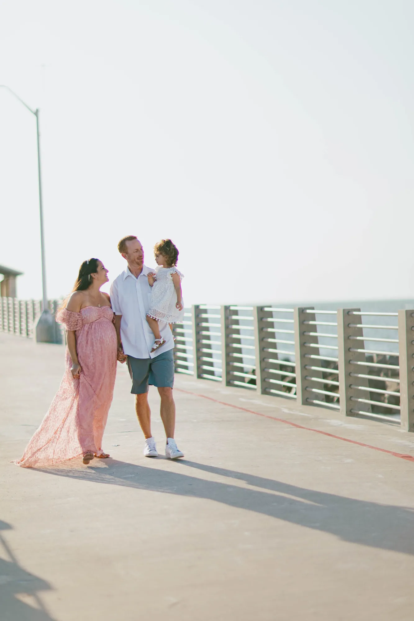 Family pausing on the pier, the father holding their toddler