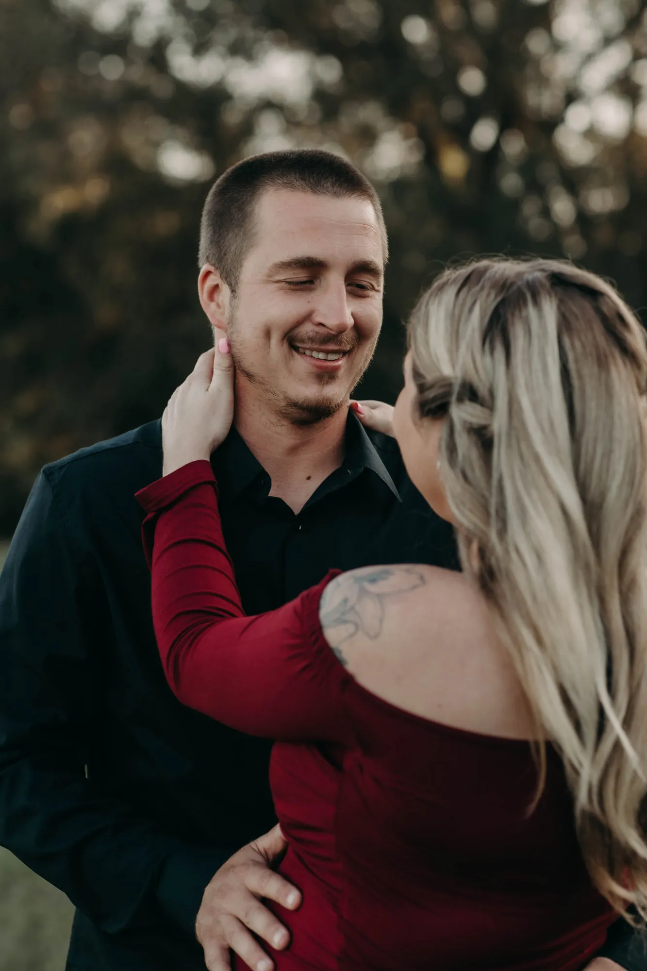 Man smiling with his eyes closed as she touches his face