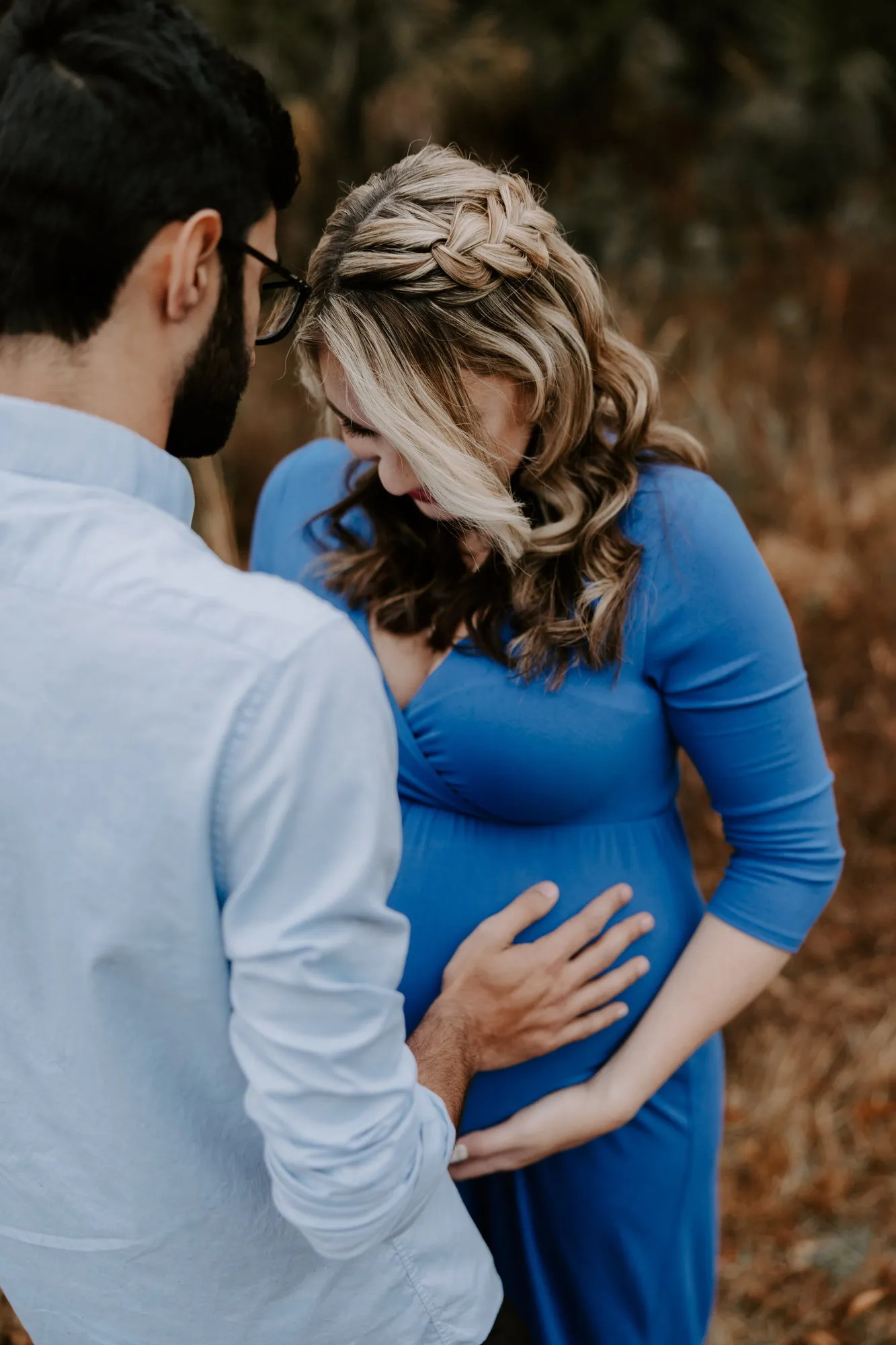 Couple looking down at her bump, his hand resting on it