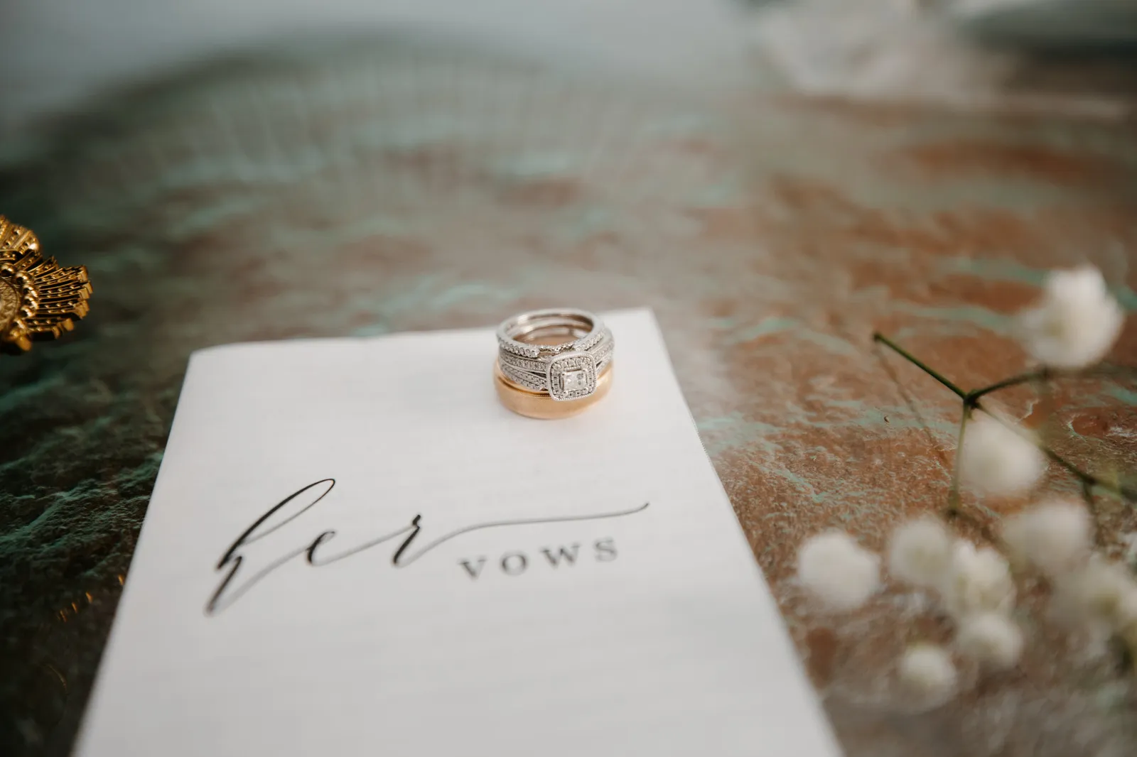 Wedding rings resting on a booklet titled "her vows"