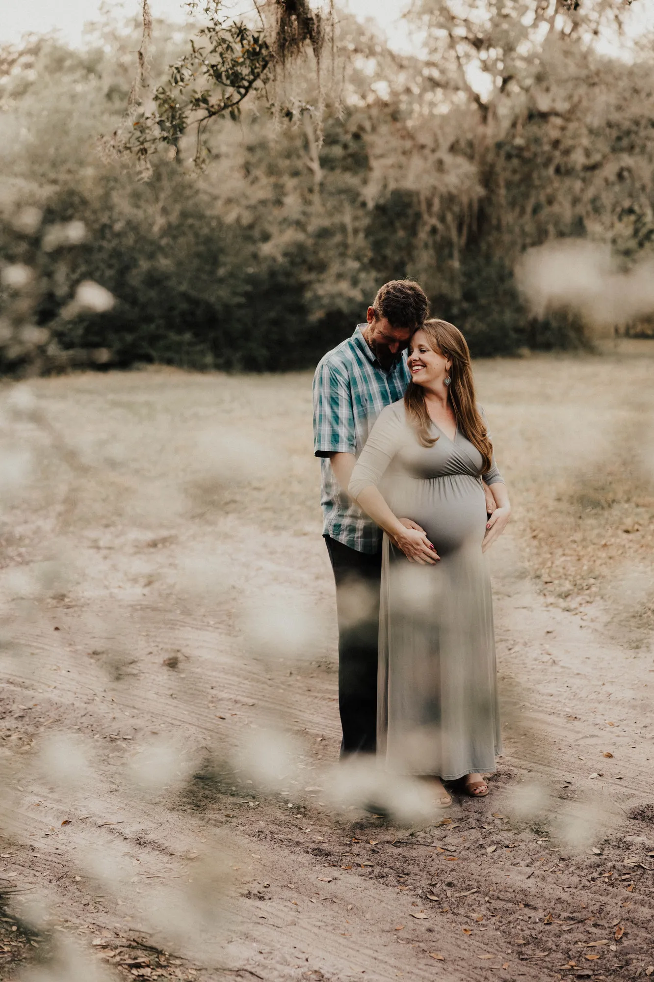 Father-to-be kissing her temple on a sandy track