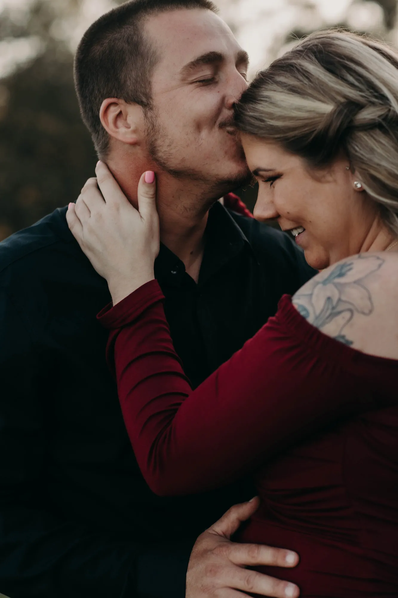 Man kissing her forehead as she holds his neck