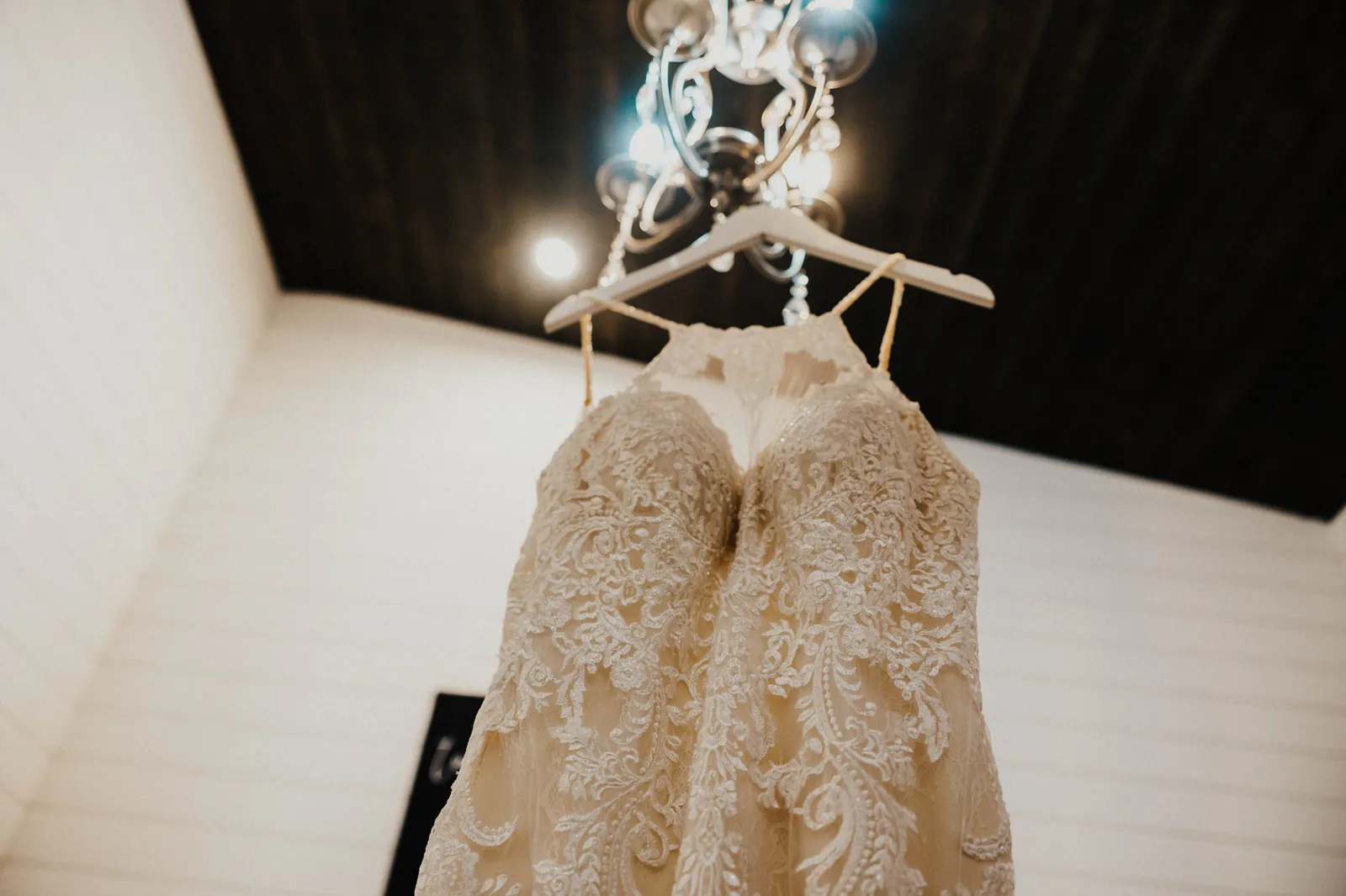 Lace wedding dress hanging from a chandelier, seen from below