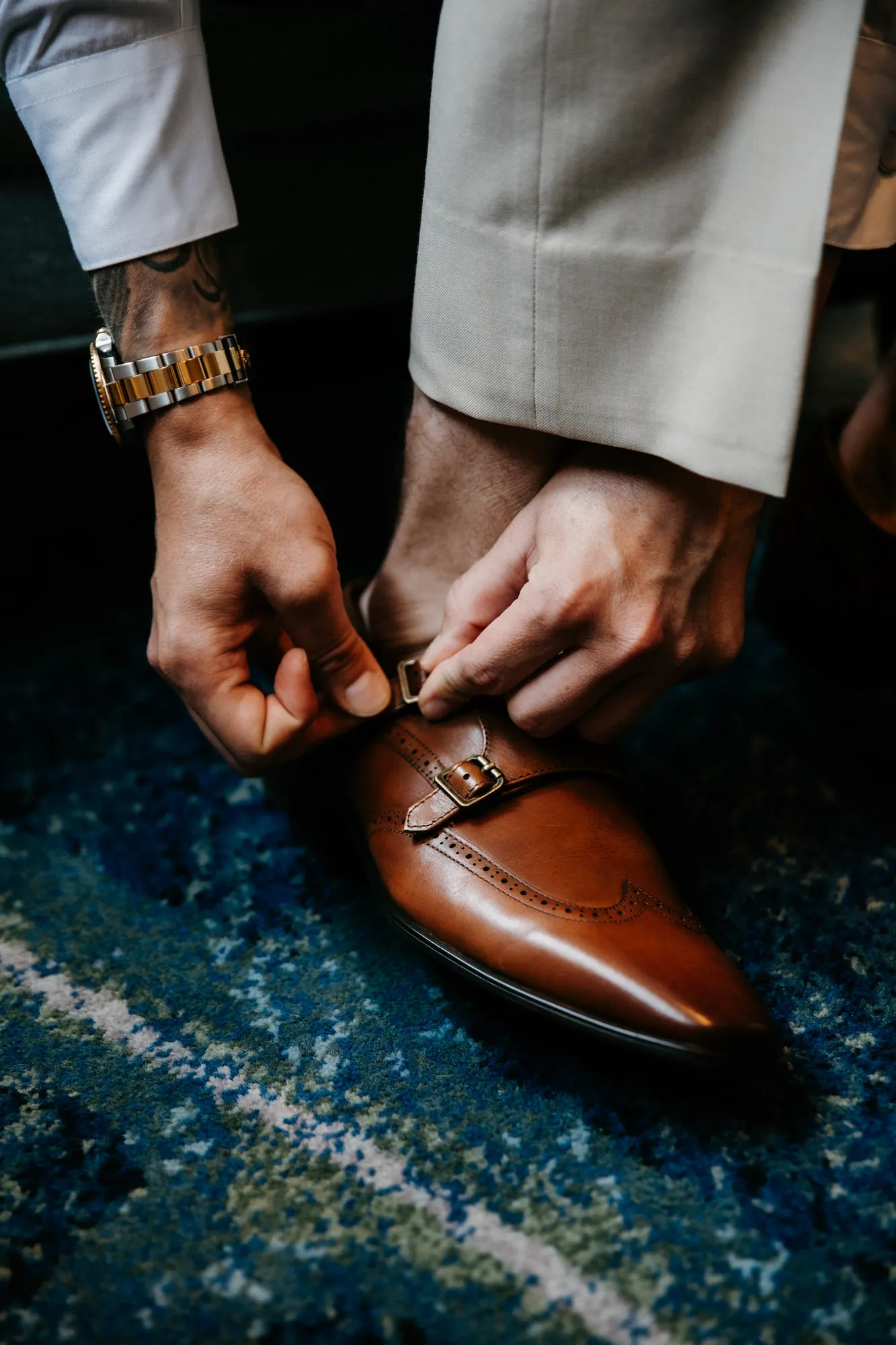 Groom fastening the buckle of his brown leather shoe