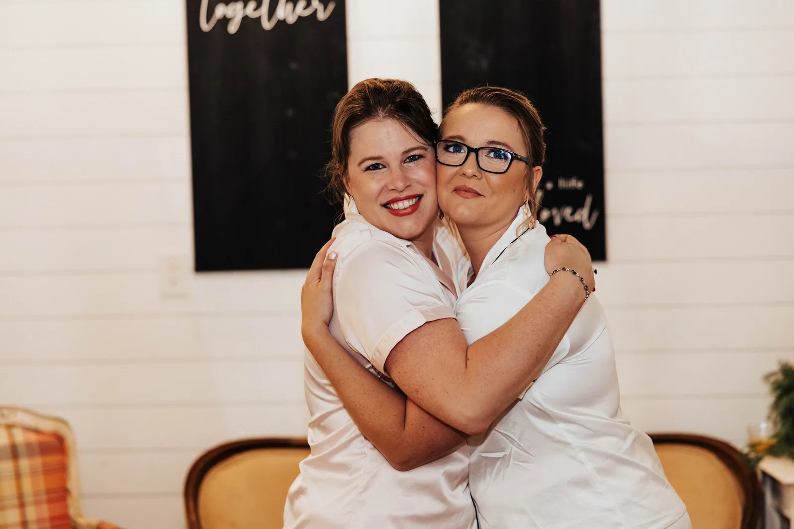 Bride hugging a bridesmaid, both in white pajamas