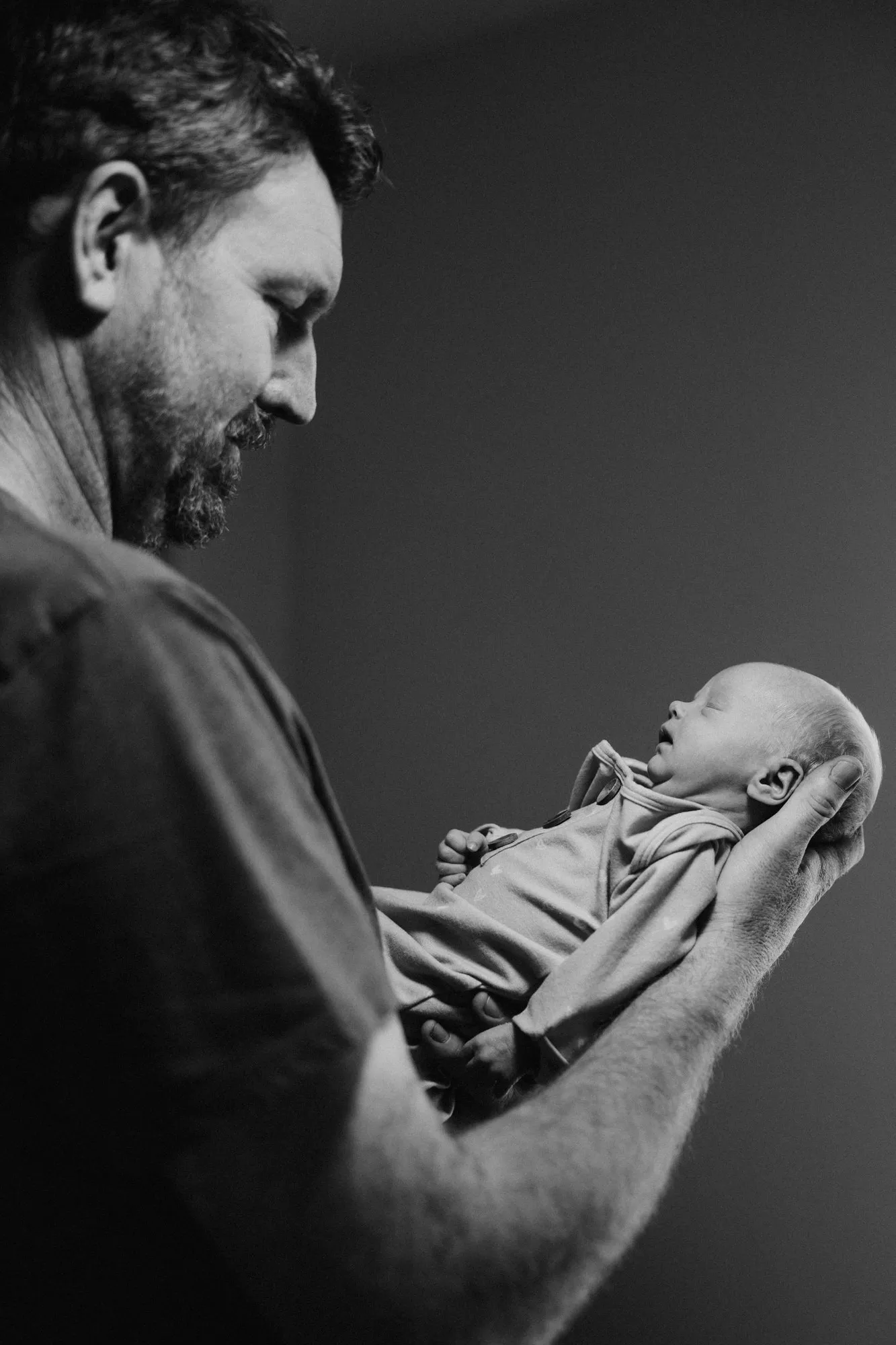 Father cradling his newborn daughter, in black and white