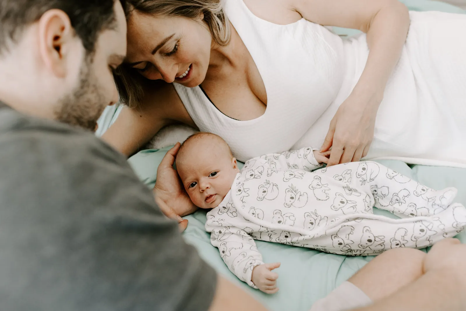 Parents lying beside their newborn son on the bed