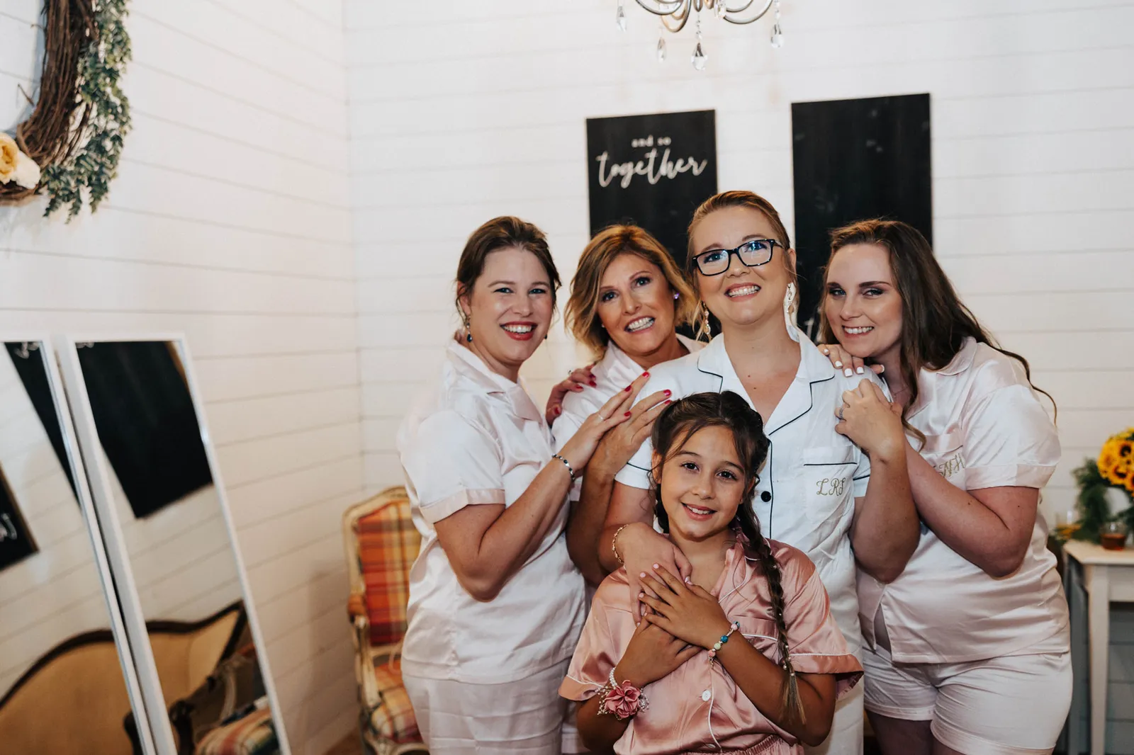 Bride laughing with her bridesmaids and flower girl while getting ready
