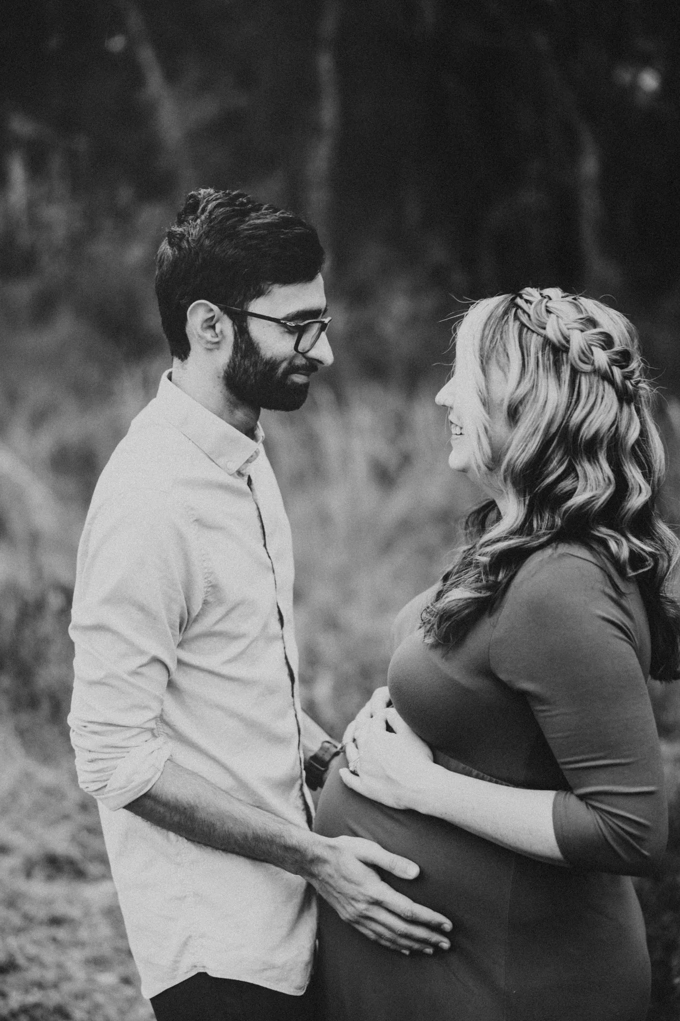 Expectant couple smiling at each other, in black and white
