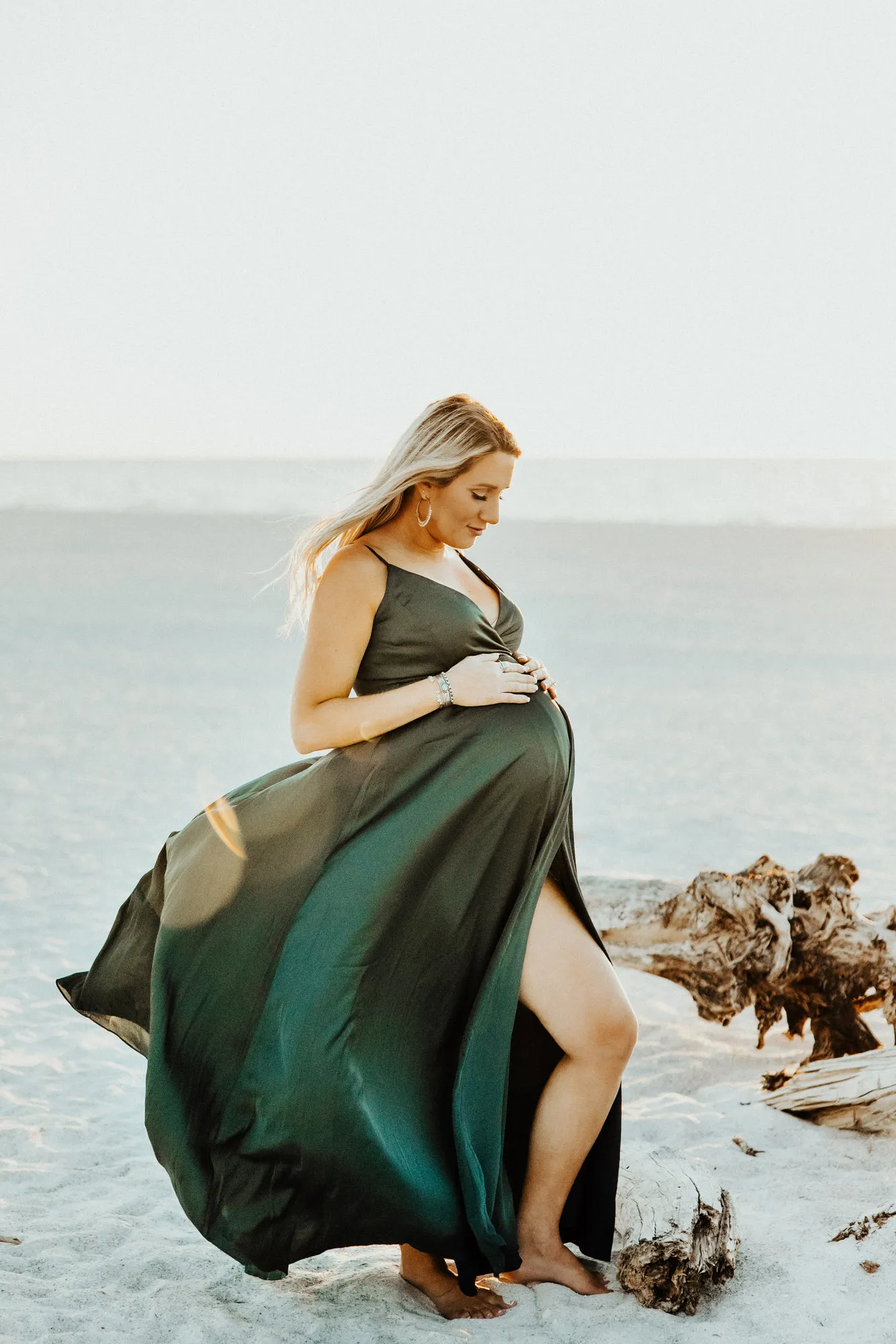 Expectant mother in an emerald gown at the water's edge