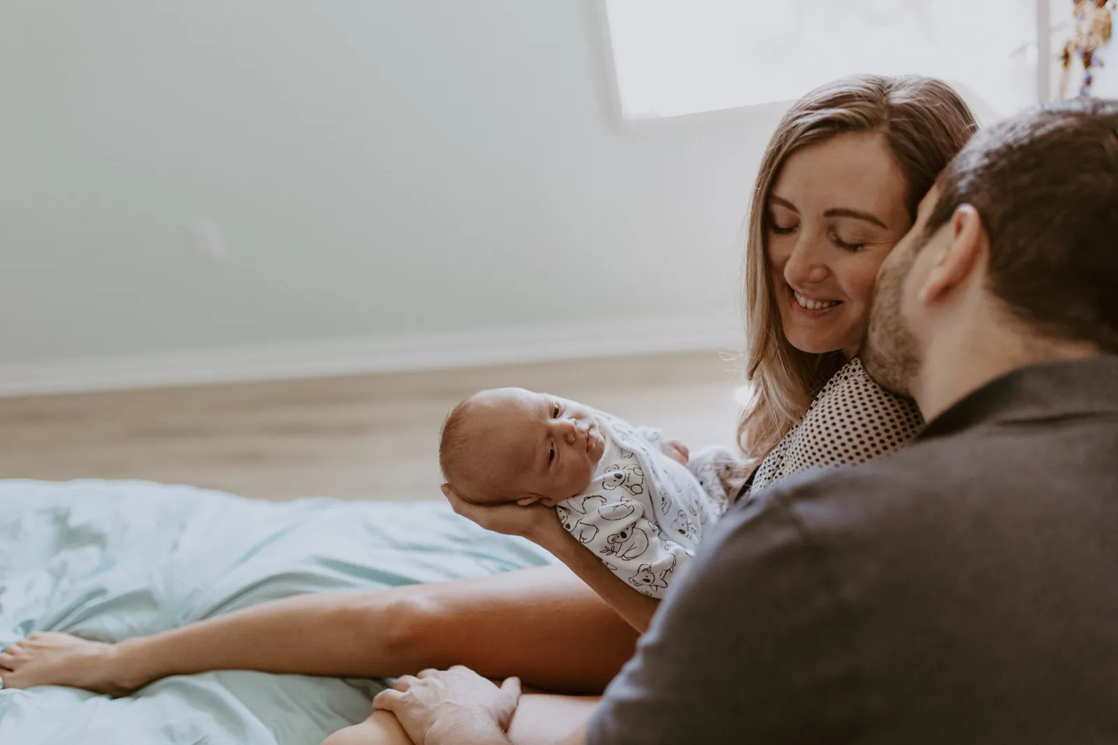 Father kissing the mother's cheek while she holds their newborn