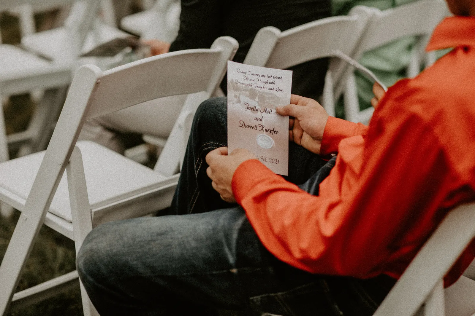 Guest in an orange shirt reading the ceremony program