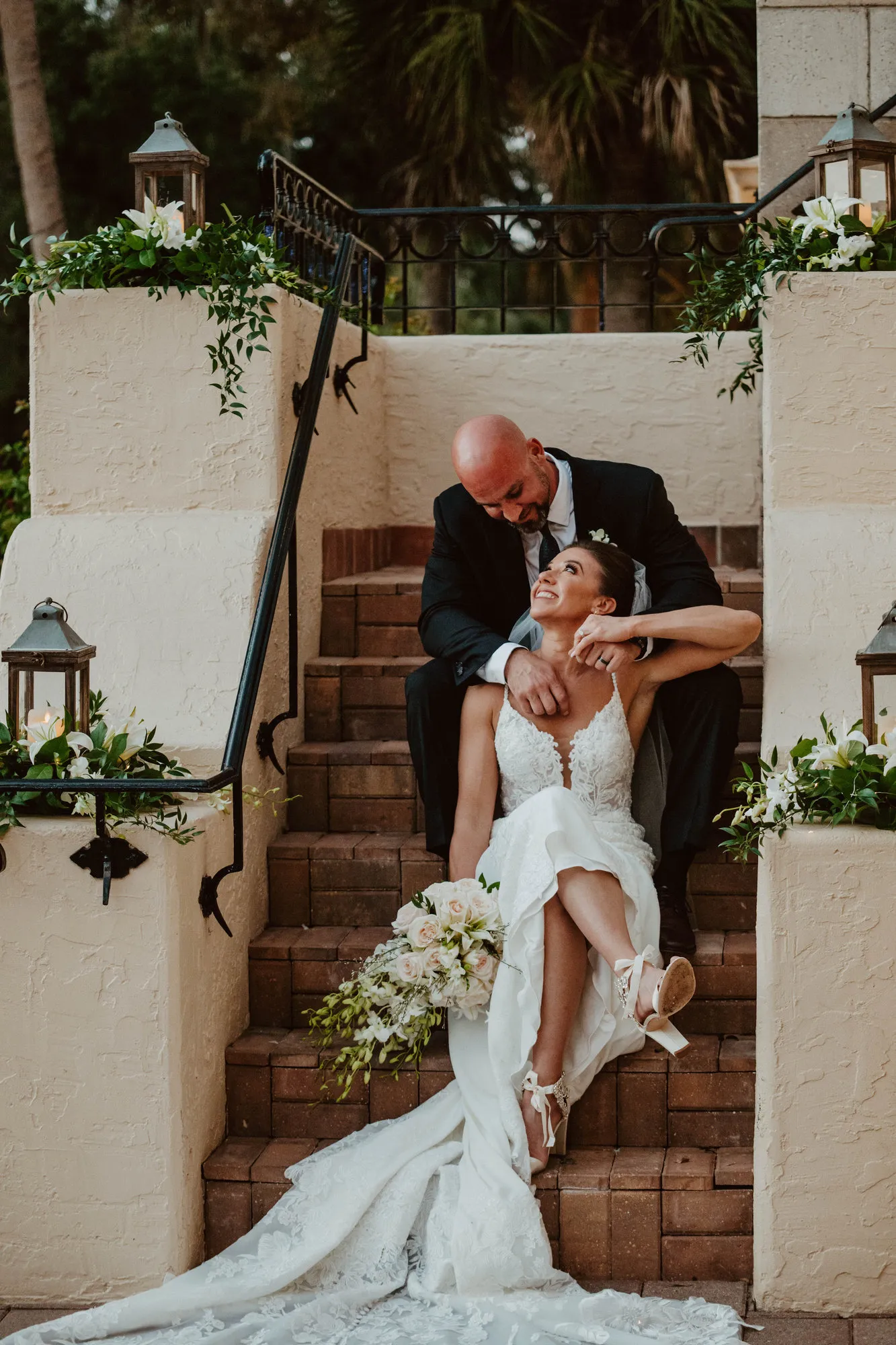 Groom leaning down from the step above to kiss his bride on the brick staircase