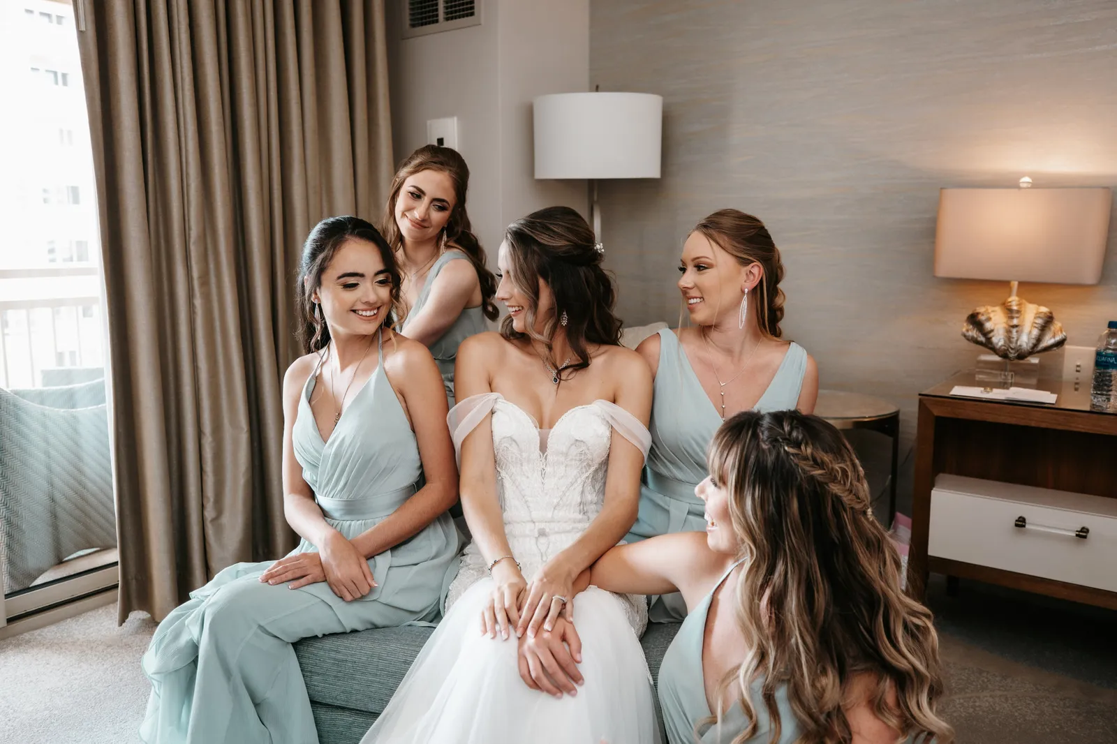 Bride sitting with her bridesmaids in sage green dresses
