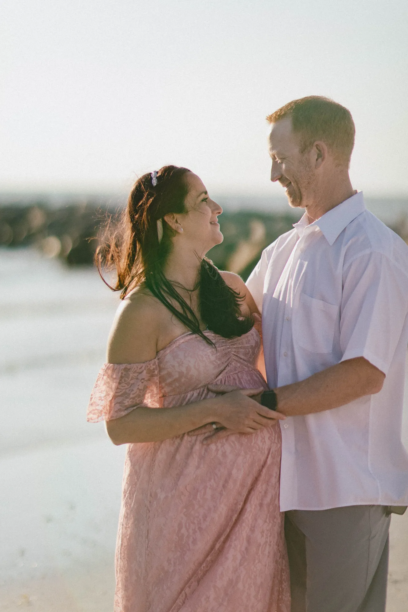 Couple smiling at each other, his hand on her bump