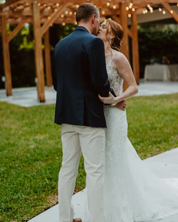 Bride and groom kissing in front of the string-lit pergola at Bakers Ranch