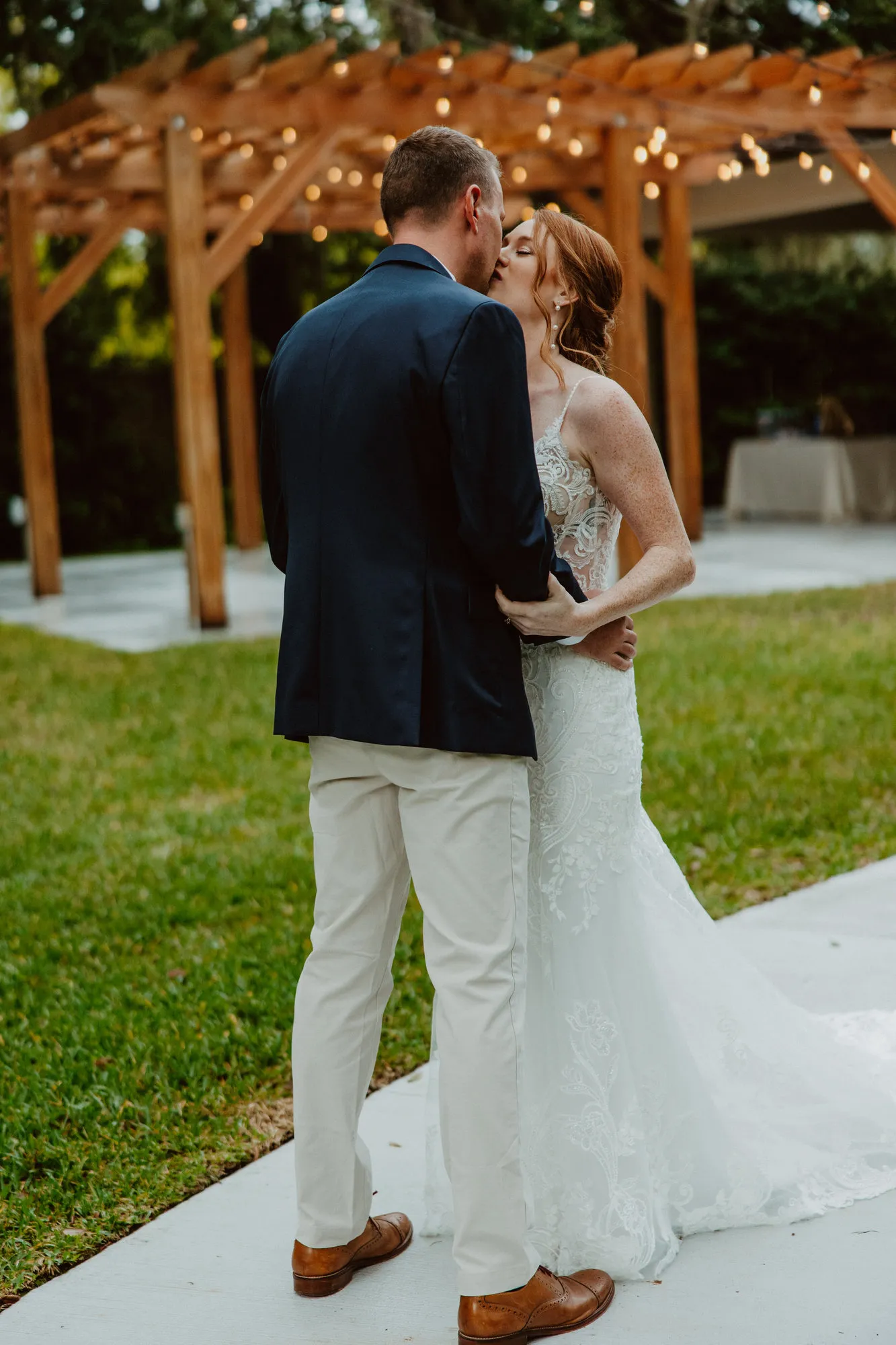 Bride and groom kissing in front of the string-lit pergola at Bakers Ranch