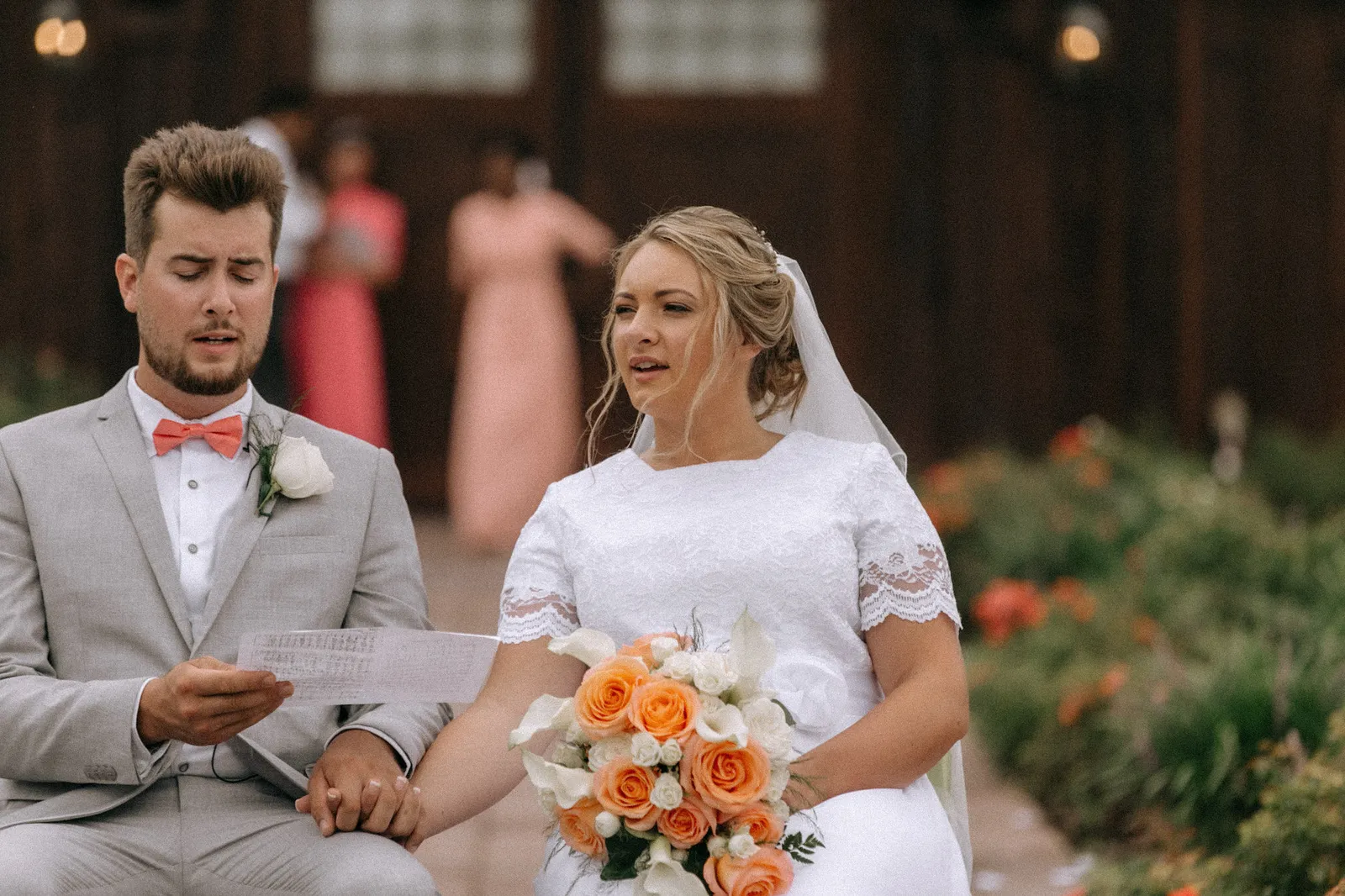Bride and groom seated side by side, the groom reading from a card