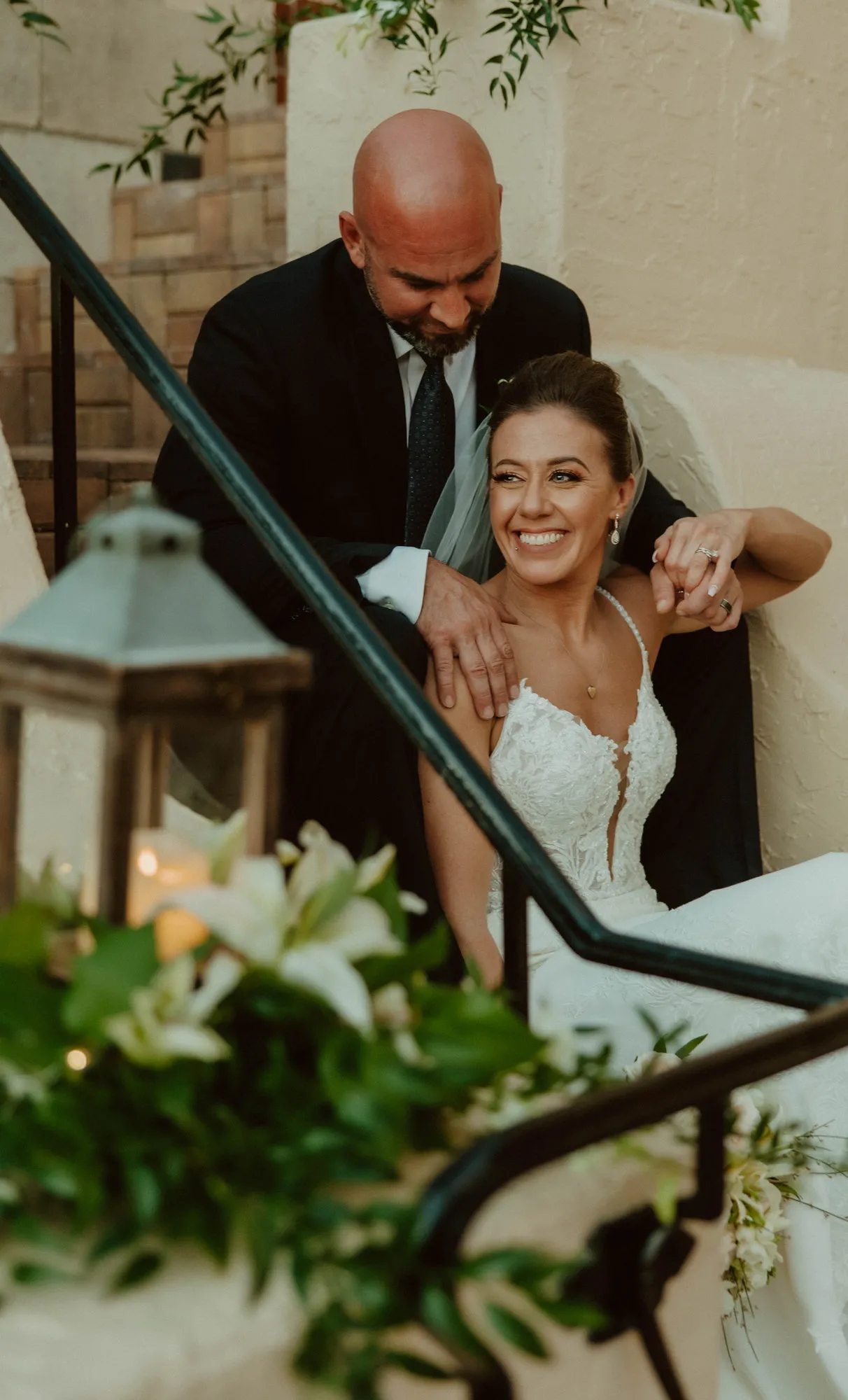 Bride laughing as the groom leans over her shoulder on the staircase