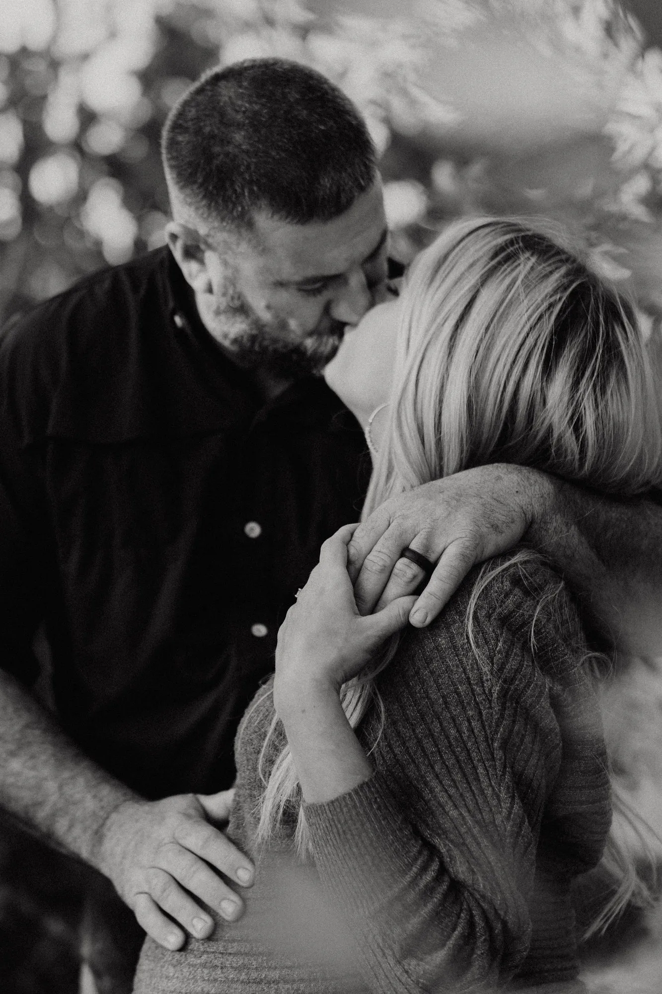 Couple kissing, her hand held in his at her shoulder, in black and white