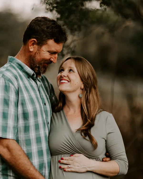Expectant mother smiling up at her husband as he holds her bump