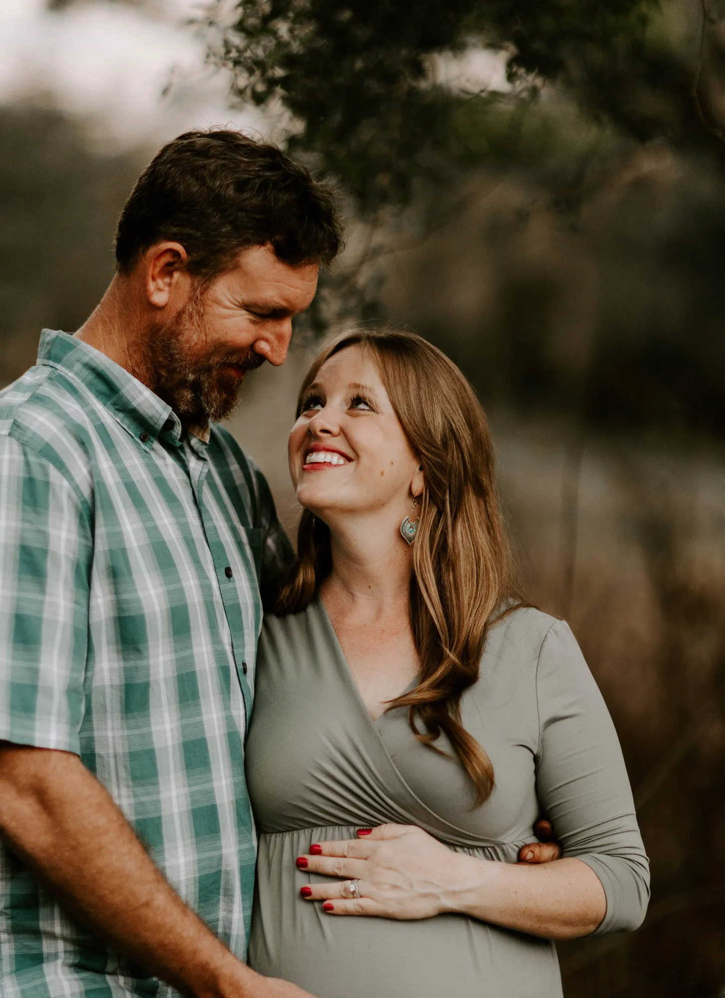 Expectant mother smiling up at her husband as he holds her bump