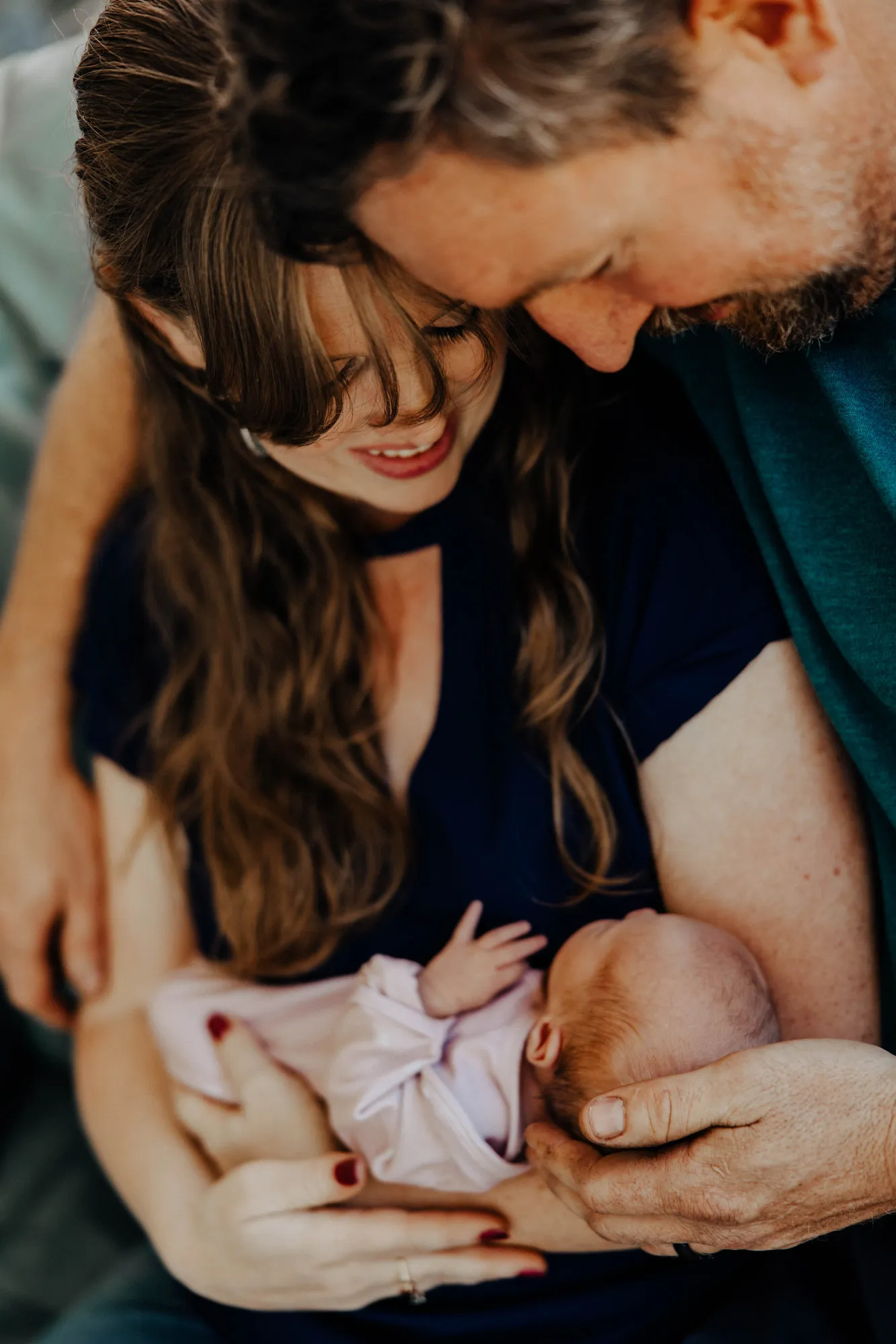 Parents with their heads together over their newborn daughter