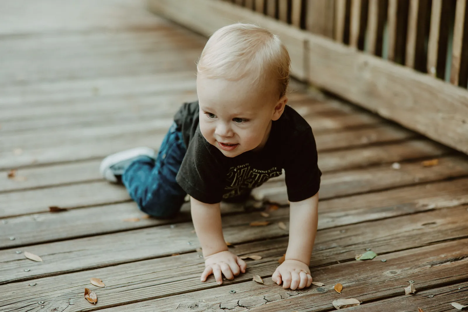 Toddler crawling along a wooden boardwalk