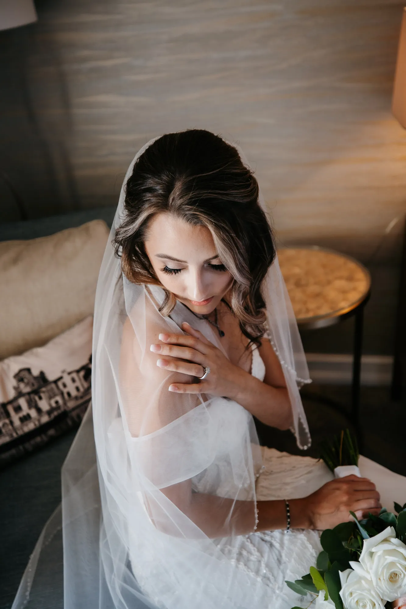 Bride in her veil looking down, hand to her chest