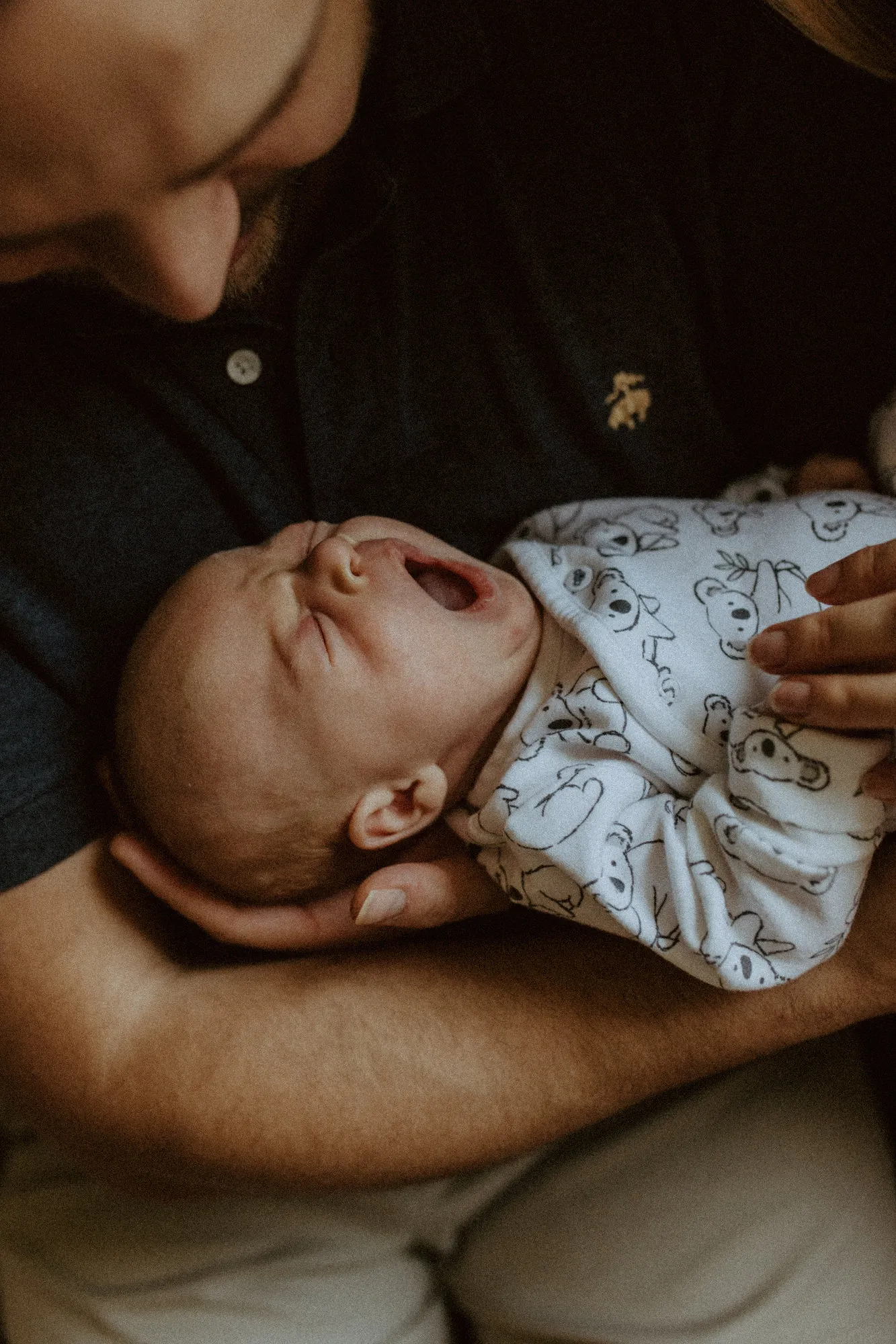 Newborn yawning in his father's arms