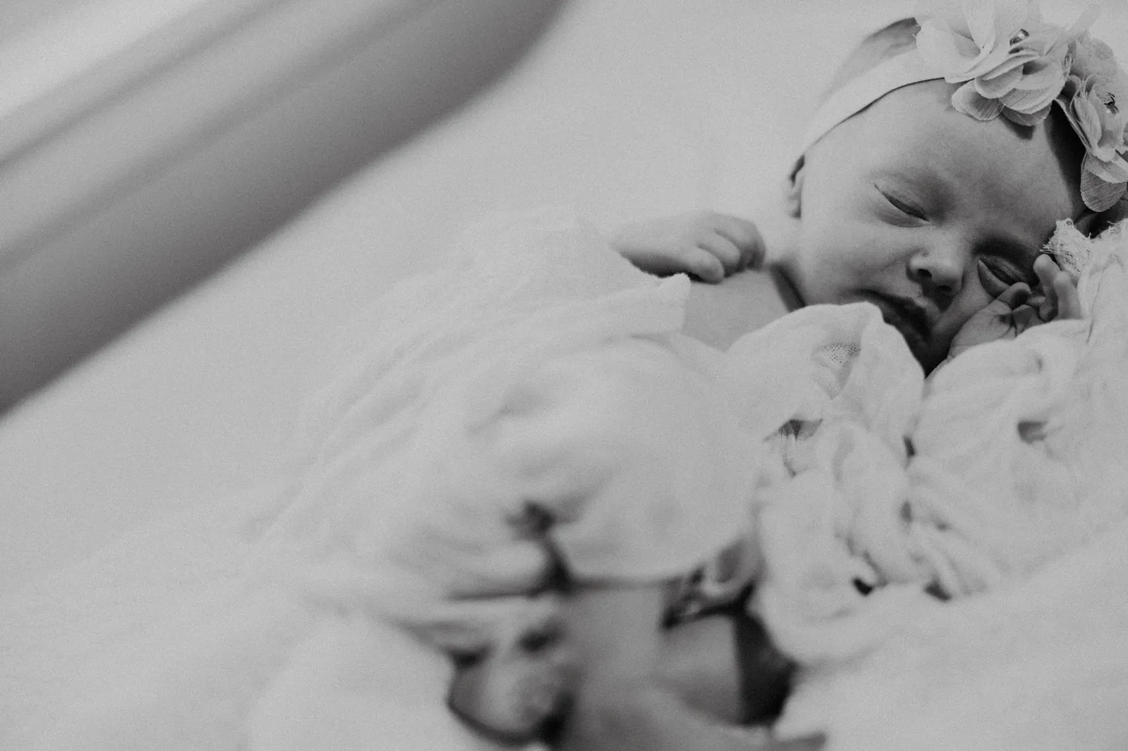 Sleeping newborn in a flower headband, in black and white