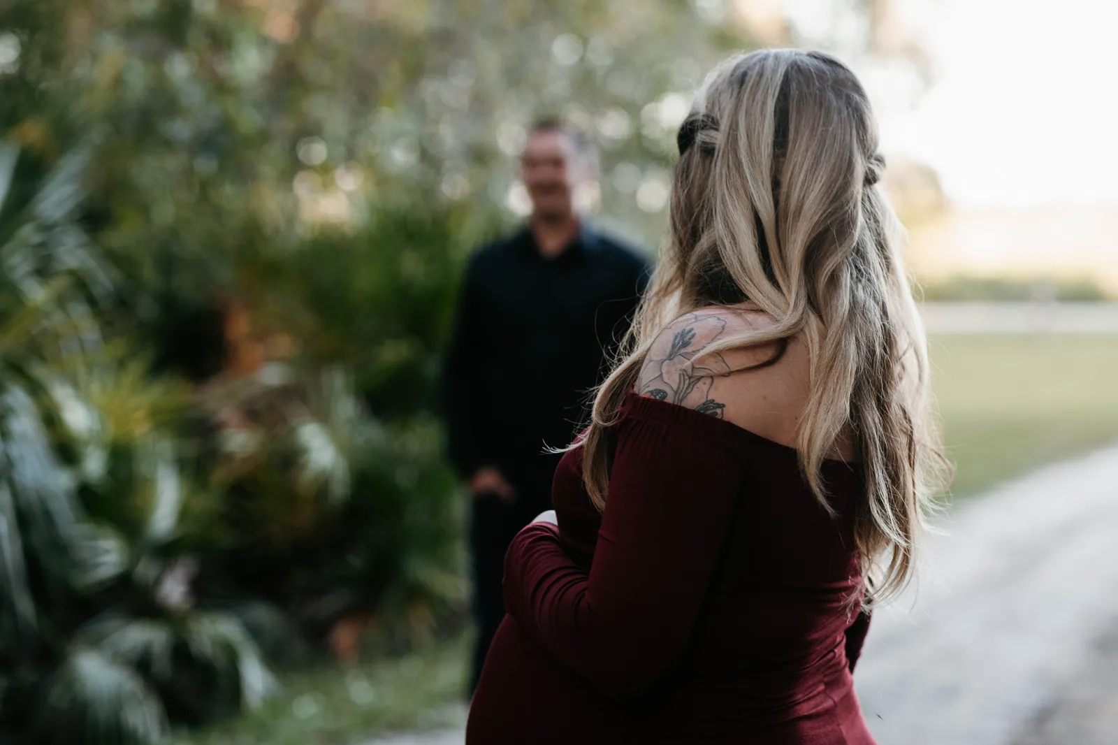 Expectant mother seen from behind, her partner out of focus ahead of her