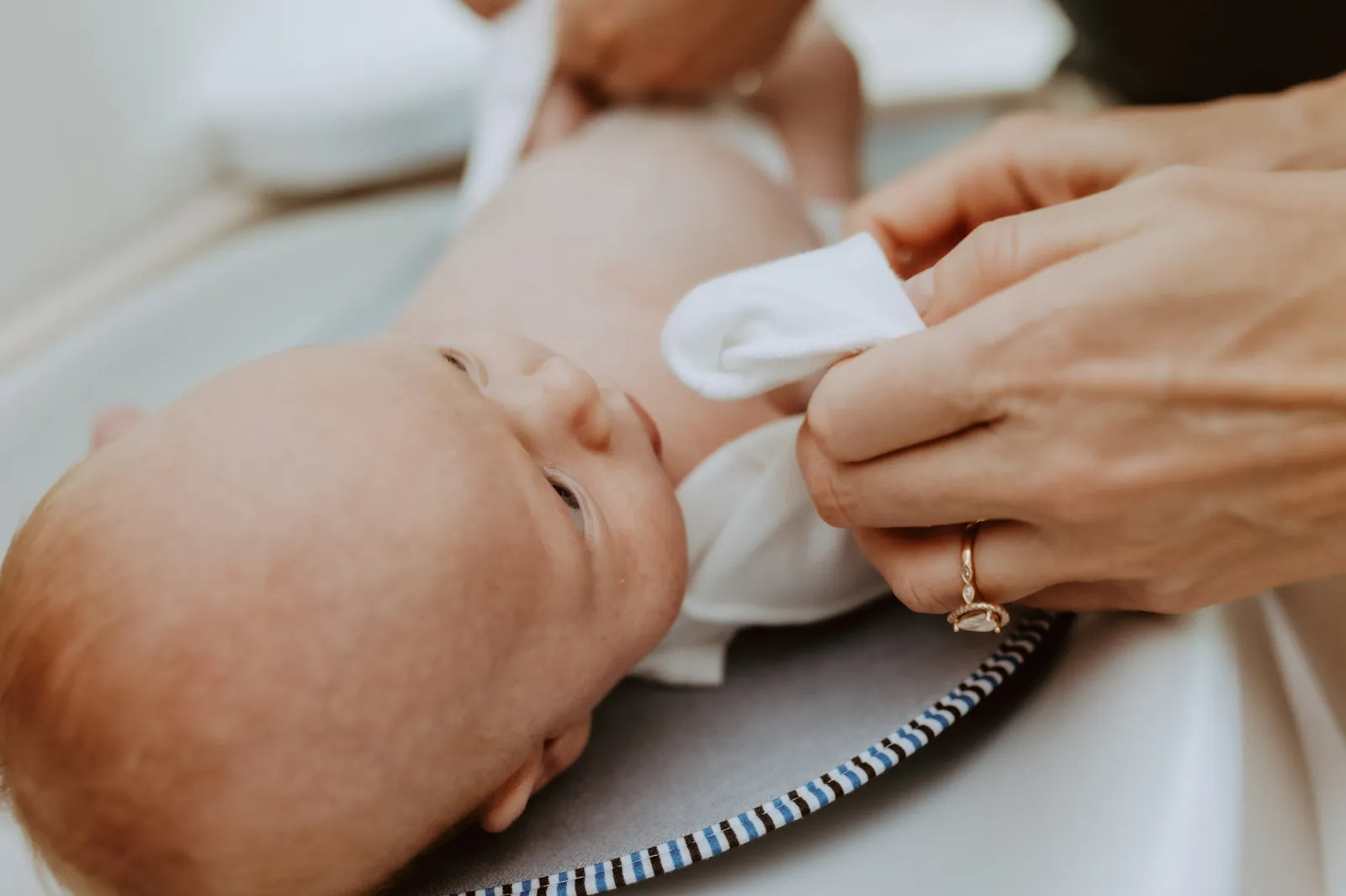 Newborn lying on the changing mat while a parent changes him