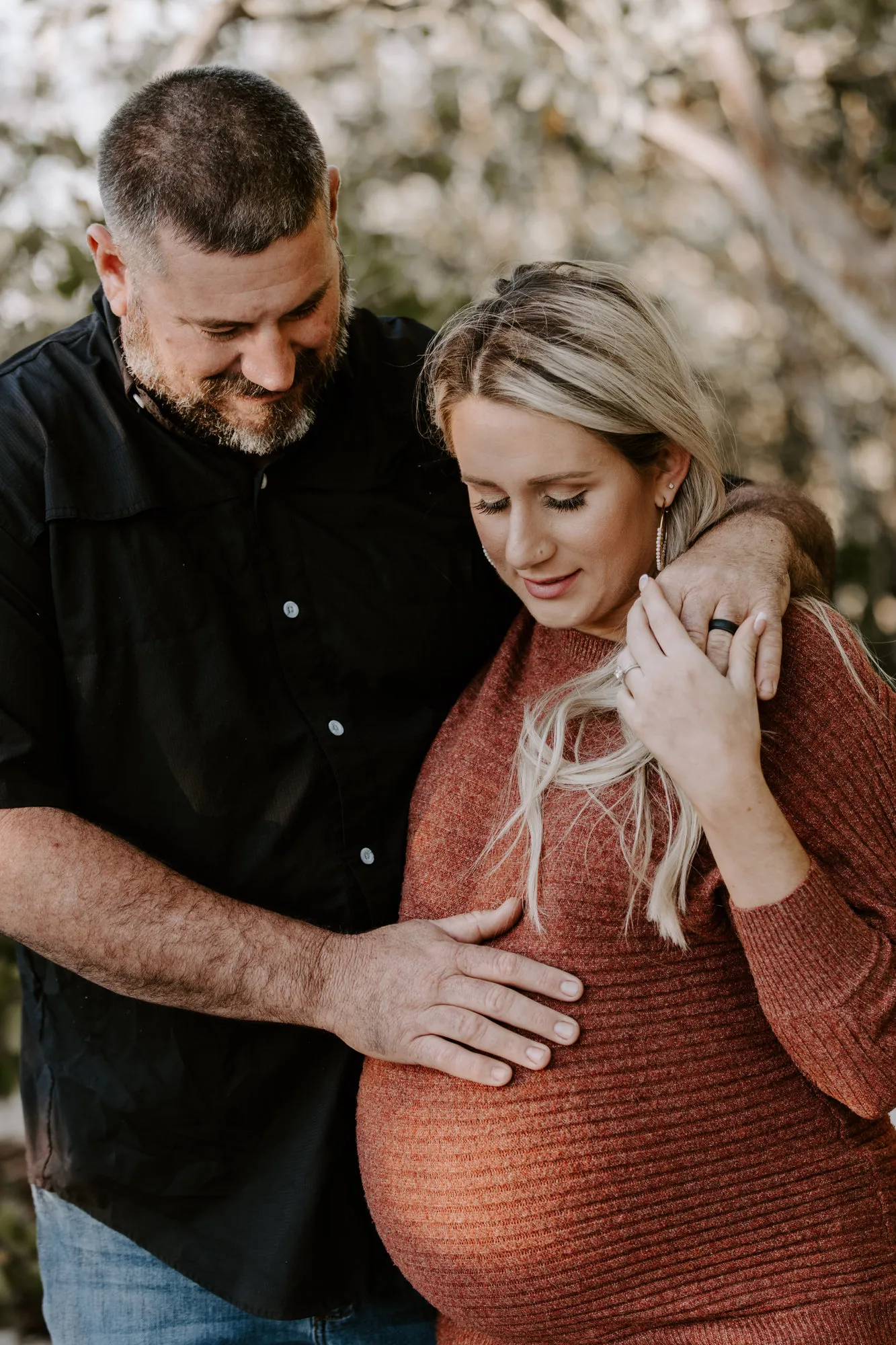 Father-to-be resting his hand on her bump as they smile