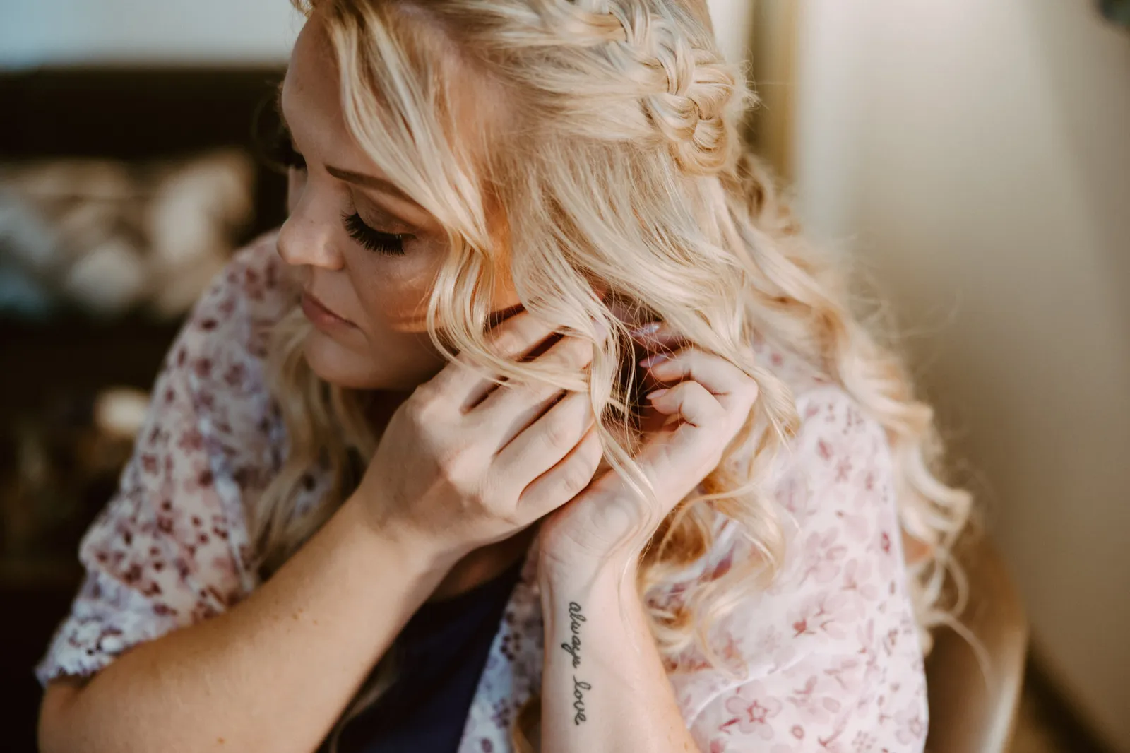 Bride with curled blonde hair putting on an earring