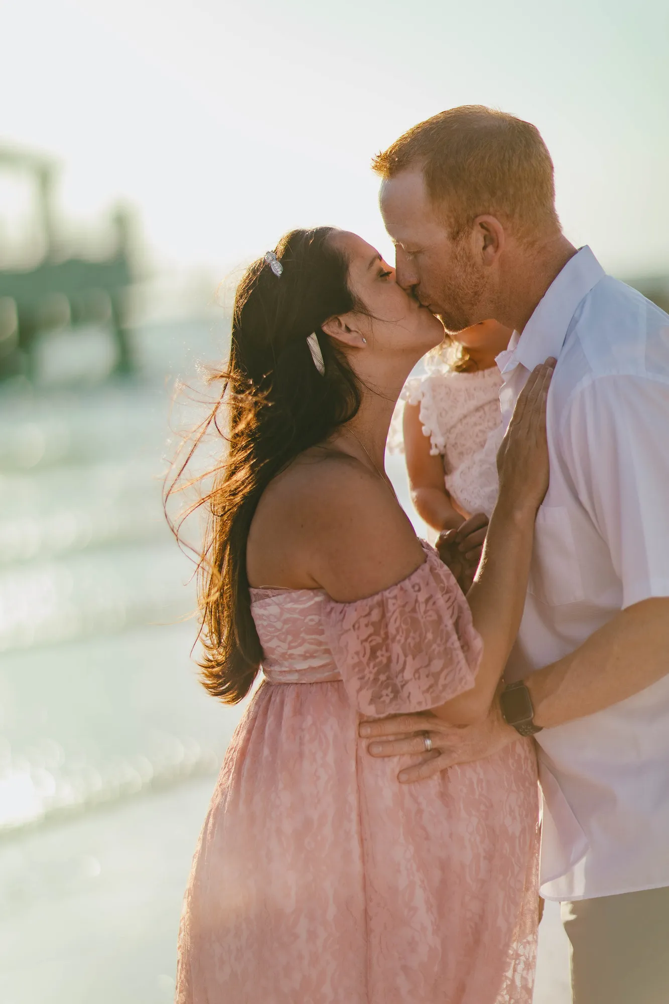 Couple kissing with the Fort De Soto pier behind them
