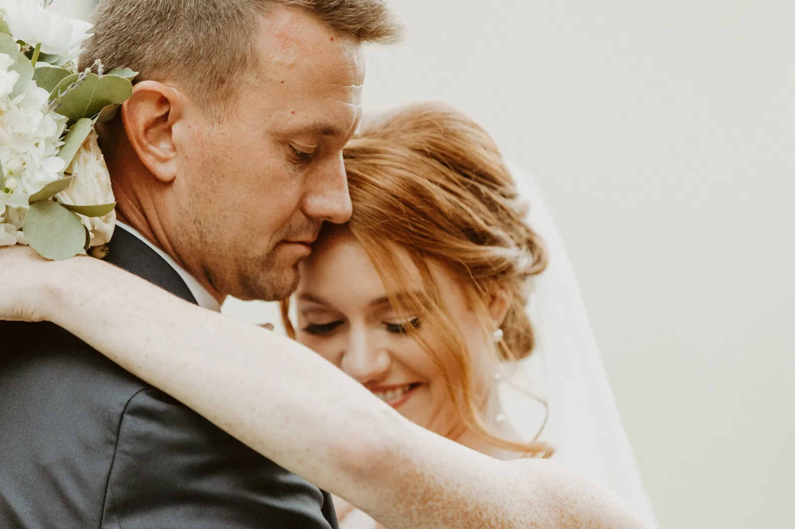 Groom resting his head against his smiling bride's