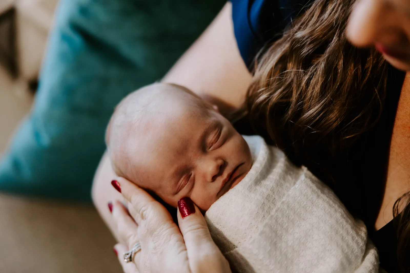 Sleeping newborn held against her mother's shoulder