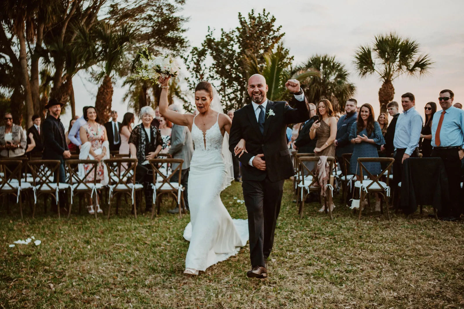 Bride and groom cheering as they walk back up the aisle past their guests