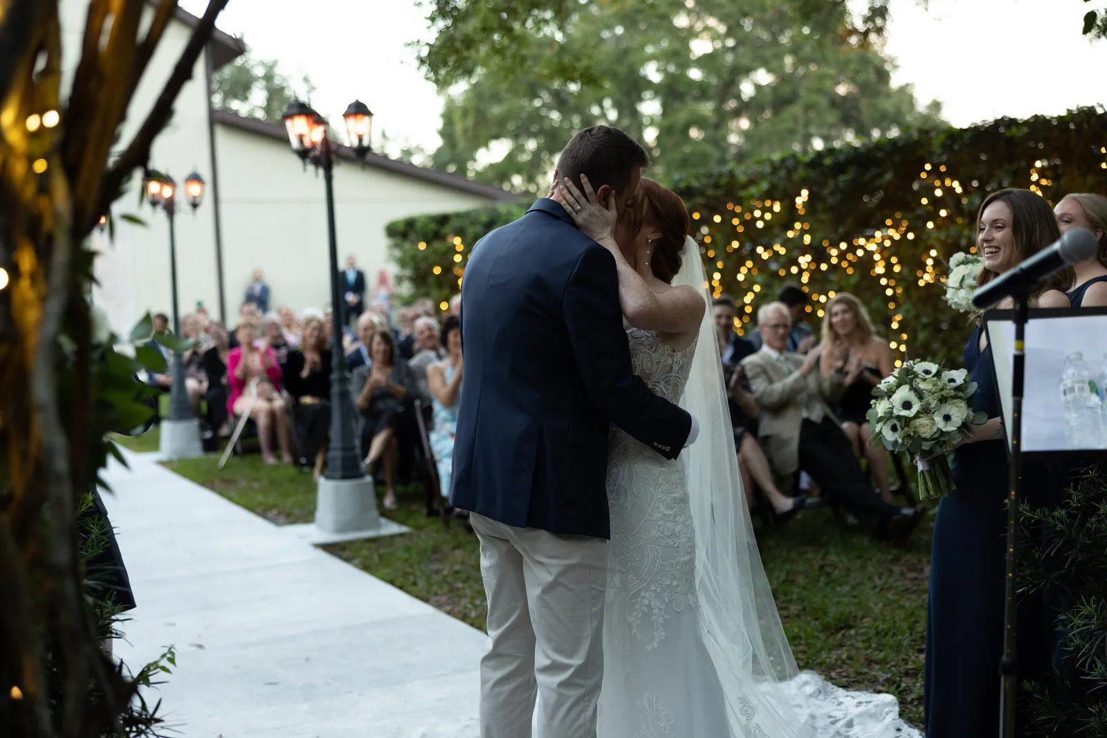 Bride and groom embracing at the ceremony as guests watch