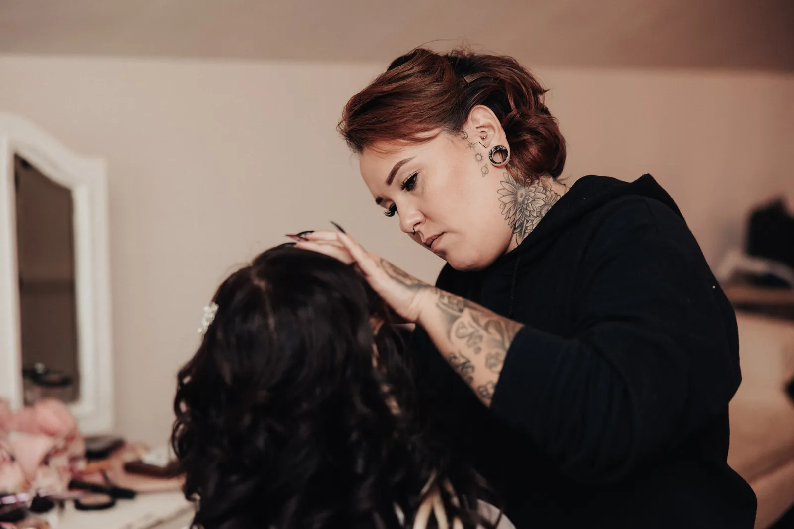 Makeup artist with tattooed hands applying the bride's makeup